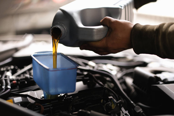 Foreman pours car oil into engine through watering can closeup - Photo, image
