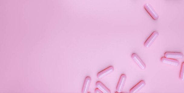 Top view pink capsules pill on pink background. Health care web banner. Vitamins and supplements for women concept. Pharmaceutical industry. Breast cancer or woman health topics. Healthy life. - Фото, изображение