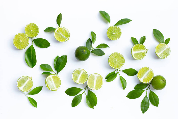 Fresh limes with green leaves on white background. Top view - Zdjęcie, obraz