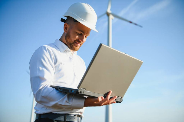 Engineer standing and hoding laptop with wind turbine. - Foto, imagen