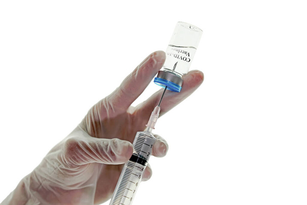 Uzavřete lahvičku s vakcínami a injekční stříkačku s podkožní injekcí v rukou s rukavicí, izolovanou na bílém pozadí. Covid-19 nebo koncept nemoci. - Fotografie, Obrázek