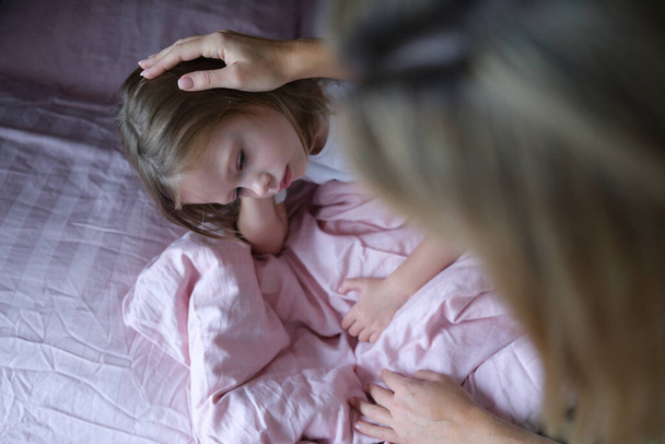Mom puts sad girl on head before going to bed. - Foto, Bild