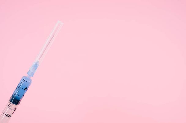 an isolated injection syringe on a pink background with text space - Фото, изображение