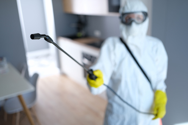 Person in protective suit and mask disinfects kitchen - Foto, Bild