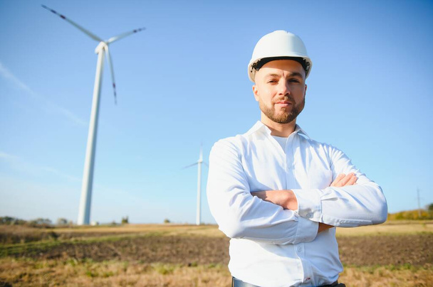 Engineer in wheat field checking on turbine production - Photo, image