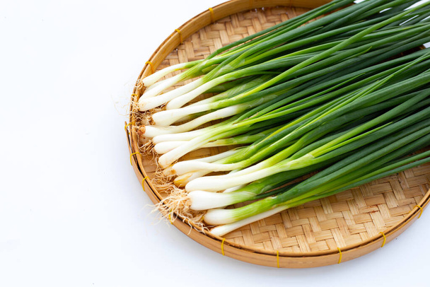 Spring onions in bamboo basket on white background - Фото, изображение