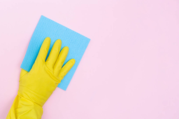 Man in rubber gloves holds a yellow rag on a pink background. Isolated. Rubber gloves for cleaning and washing. Copy space. Place for your text. Mockup. High-quality photo - Foto, Imagem