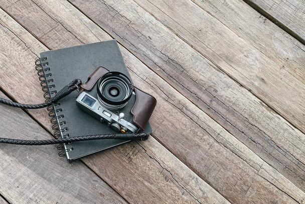 An old, vintage camera with a notepad on a wooden surface - Fotografie, Obrázek