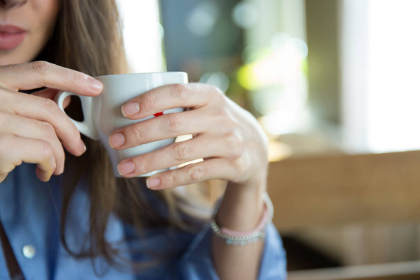 Pequena xícara branca nos dedos das mulheres fechar a imagem orientação horizontal  - Foto, Imagem