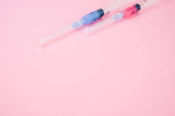 an isolated injection syringe on a pink background with text space - Foto, afbeelding
