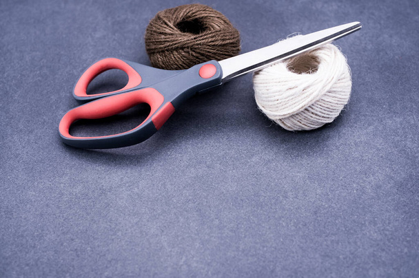 multicolor decoration yarns with scissors on a dark stone background with copy space - Foto, Bild