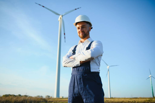 Engineer is checking energy production on wind turbine. Worker in windmills park in helmet. - Foto, Imagem