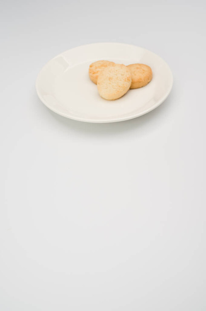 white plate with biscuits on a white background with copy space - Valokuva, kuva