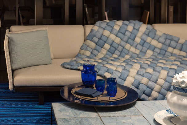 Acogedor salón contemporáneo con elegante sofá, manta suave, mesa de centro con accesorios de decoración - Foto, imagen