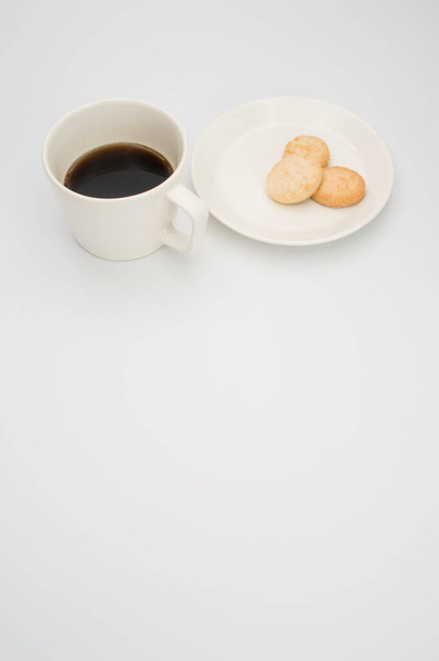 black coffee in a mug and plate with biscuits on a white background with copy space - Photo, Image
