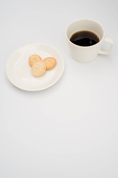 black coffee in a mug and plate with biscuits on a white background with copy space - Fotoğraf, Görsel