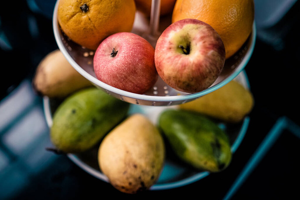 A variety of fresh fruits in a container on a blurred background - Фото, зображення