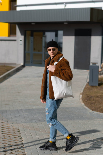 Hipster va a la tienda con una bolsa reutilizable. Foto de alta calidad - Foto, Imagen