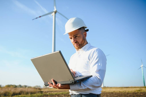 Young engineer man looking and checking wind turbines at field - Foto, immagini