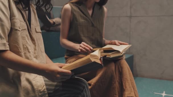 Midsection slow mo lövés két felismerhetetlen női egyetemi hallgatók ül a lépcsőn fordult könyv oldalak tanulás közben - Felvétel, videó