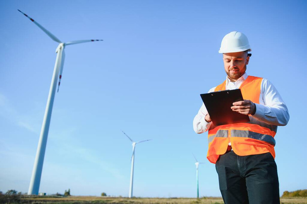 Young engineer man looking and checking wind turbines at field - Photo, image