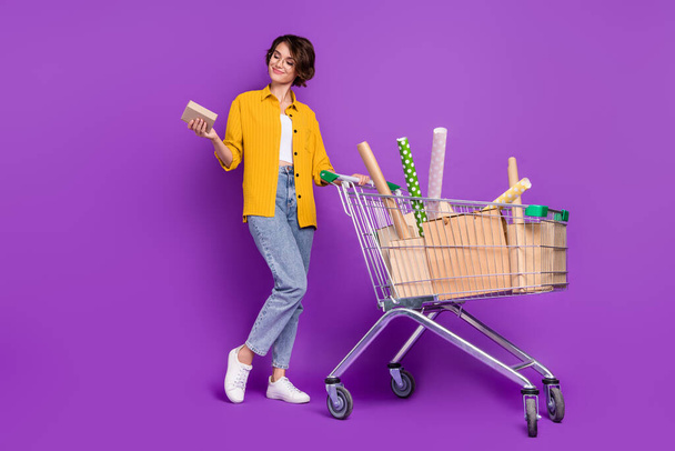 Full length body size view of attractive cheery girl carrying buyings isolated over bright violet purple color background - Foto, Bild