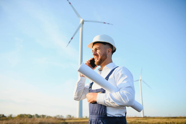Young Businessman Talking to Manager Using Smart Telephone On Wind Turbine Field, Green Energy Concept - Fotografie, Obrázek