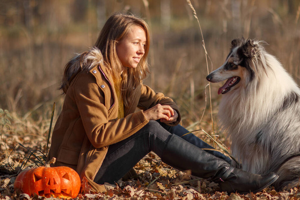 Portrait of a Blue Merle Rough-haired Merle Collie and a girl in an autumn park on a Halloween holiday. - Photo, image
