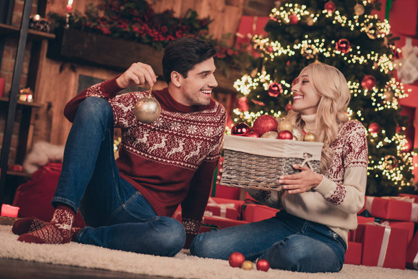 Photo of attractive funny young wife husband wear print sweaters smiling decorating noel tree indoors house home room - Foto, imagen