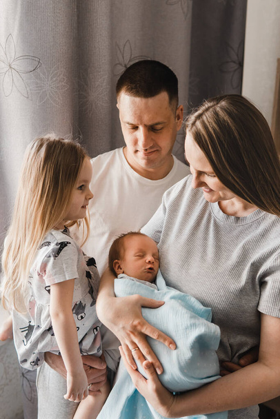 Portrait of loving family with newborn son and infant daughter. Happy caucasian family of four people. Sister meets her newborn brother. Selective focus - Photo, image