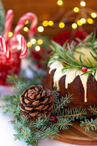 Christmas caramel cake, decorated with white chocolate, cranberry, rosemary and New Year decorations. Festive baked goods. Soft selective focus. Vertical - Foto, Bild