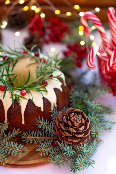Weihnachtskaramellkuchen, dekoriert mit weißer Schokolade, Preiselbeeren, Rosmarin und Neujahrsdekorationen. Festliches Gebäck. Weiche selektive Fokussierung. Vertikal - Foto, Bild
