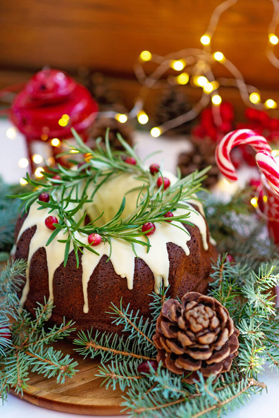 Christmas caramel cake, decorated with white chocolate, cranberry, rosemary and New Year decorations. Festive baked goods. Soft selective focus. Vertical - Fotó, kép