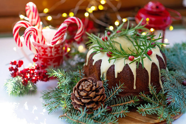 Christmas caramel cake, decorated with white chocolate, cranberry, rosemary and New Year decorations. Festive baked goods. Soft selective focus. Horizontal - Photo, Image