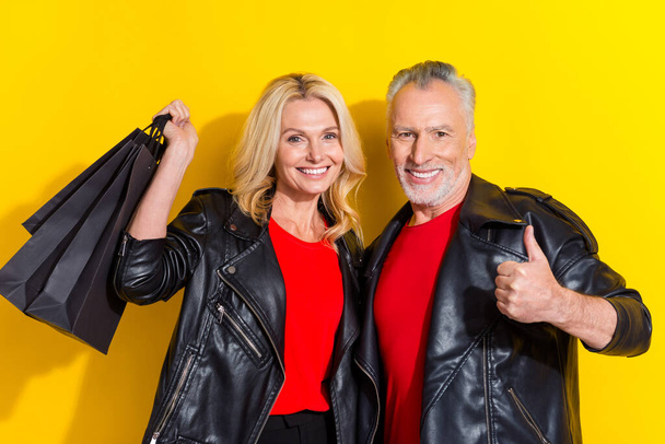 Portrait of attractive cheerful cool spouses buying goods clothes showing thumbup isolated over bright yellow color background - Fotó, kép