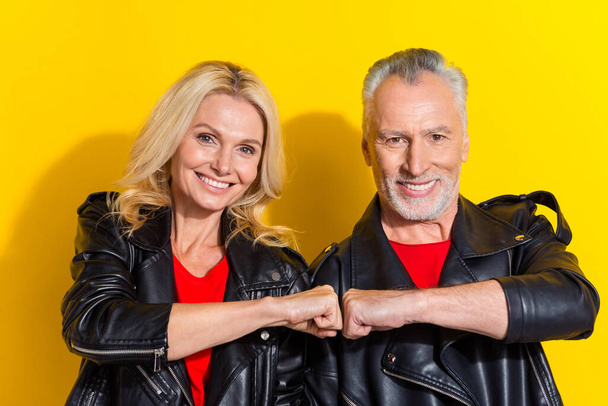 Portrait of two attractive cheerful cool grey-haired spouses putting fists deal done isolated over bright yellow color background - Foto, immagini