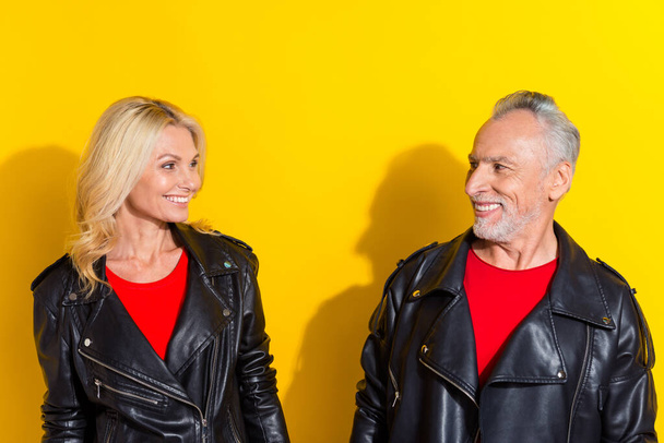Portrait of two attractive cheerful cool grey-haired spouses looking at each other isolated over bright yellow color background - Fotó, kép