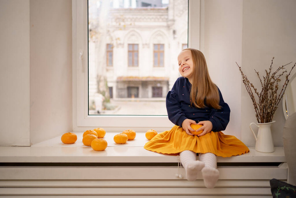 Lovely little girl sitting on the window - Photo, image