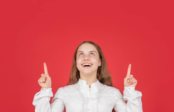 happy kid in white shirt pointing finger on red background copy space, advertising - Fotó, kép