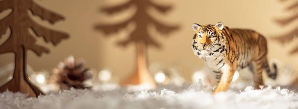 Figura de tigre, abetos de madera en nieve sobre fondo beige. Tigre símbolo del nuevo año chino 2022. Tarjeta de felicitación navideña. Banner - Foto, Imagen