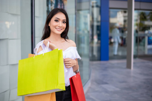 Portrait Asian beautiful happy young woman smiling cheerful and she holding shopping bags  - Photo, Image
