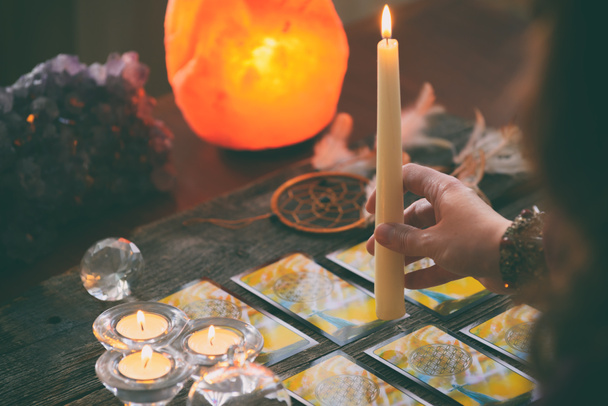 Tarot kaarten dowsing tool in de hand en kristallen als een concept van psychische adviseur of manieren van waarzeggerij - Foto, afbeelding