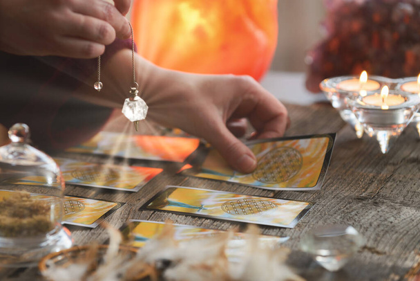 Fortune kassier met een slinger over tarot kaarten - Foto, afbeelding