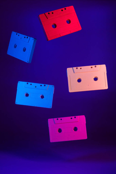 Colored audio cassettes hanging in the air against purple background - Φωτογραφία, εικόνα