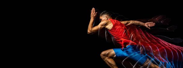 Cropped portrait of young athletic man, professional runner training isolated over black background. Stroboscope effect. Flyer - Photo, Image