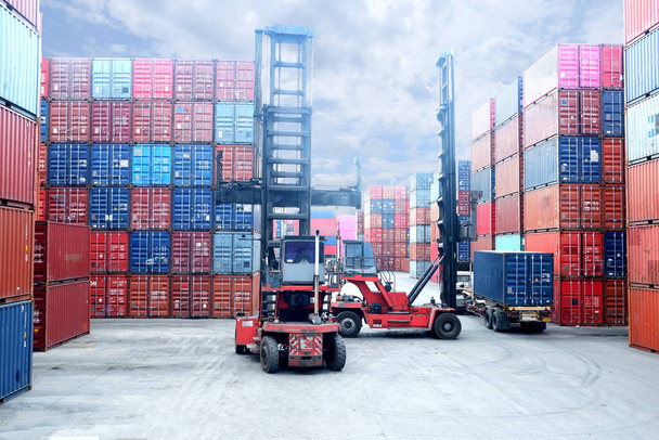 Forklift truck lifting cargo container in shipping yard or dock yard against sunrise sky with cargo container stack in background for transportation import,export and logistic industrial concept - Photo, Image