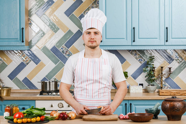 Un hombre hermoso preparando una ensalada en casa en la cocina. Cocina - Foto, imagen