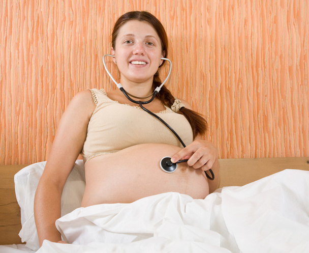 Pregnant woman listens her belly - Фото, зображення