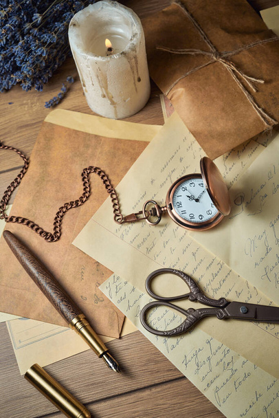 Utensílios de escrita vintage em uma mesa de madeira, relógio velho, papéis, letras, envelopes e tesouras - Foto, Imagem