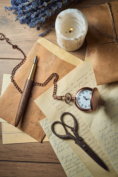 Vintage íróeszközök egy fa asztalra, régi óra, papírok, levelek, borítékok és ollók - Fotó, kép